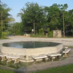 Open-air local hot-spring pool surrounded by trees in Ranong Province