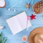 Travel notebook, walking shoes and tropical accessories arranged for planning a four-day Ranong trip