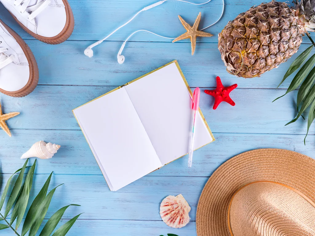 Travel notebook, walking shoes and tropical accessories arranged for planning a four-day Ranong trip